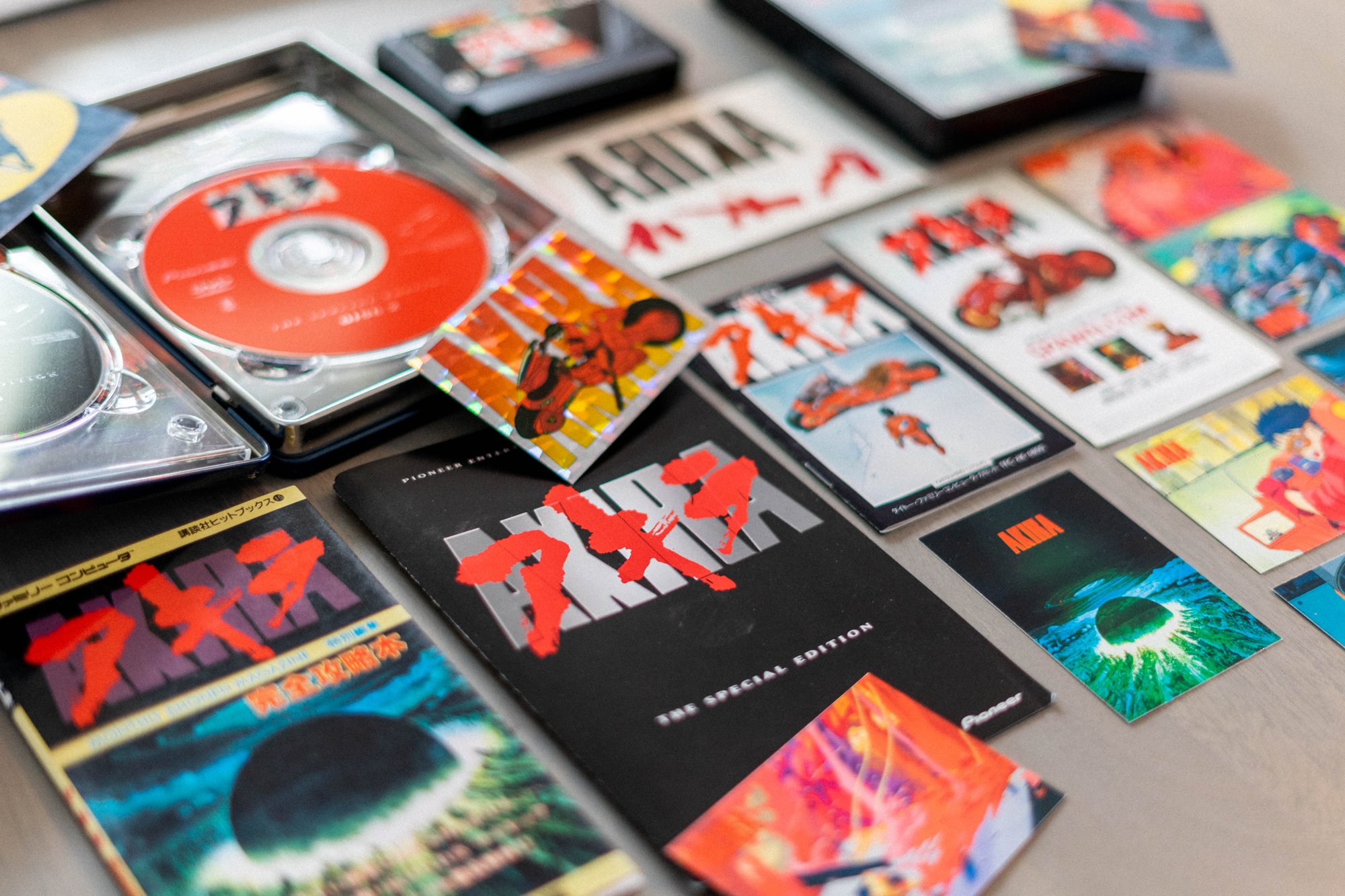 Akira collection with an open DVD case, Famicom cartridge, Japanese printed guides and illustrated cards.