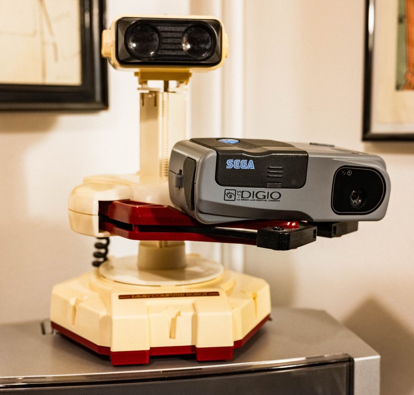 Nintendo Family Computer Robot holding a Sega Digio SJ-1 camera above a CRT television.